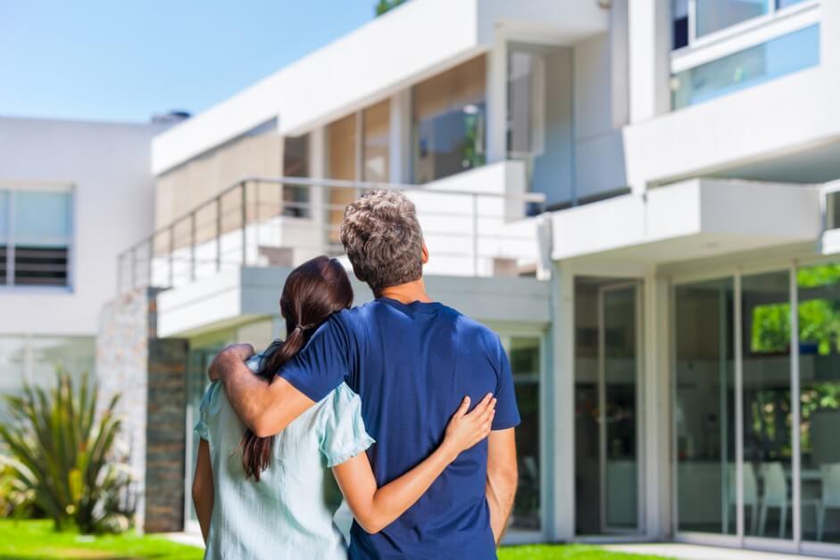 couple embracing in front of new big modern house